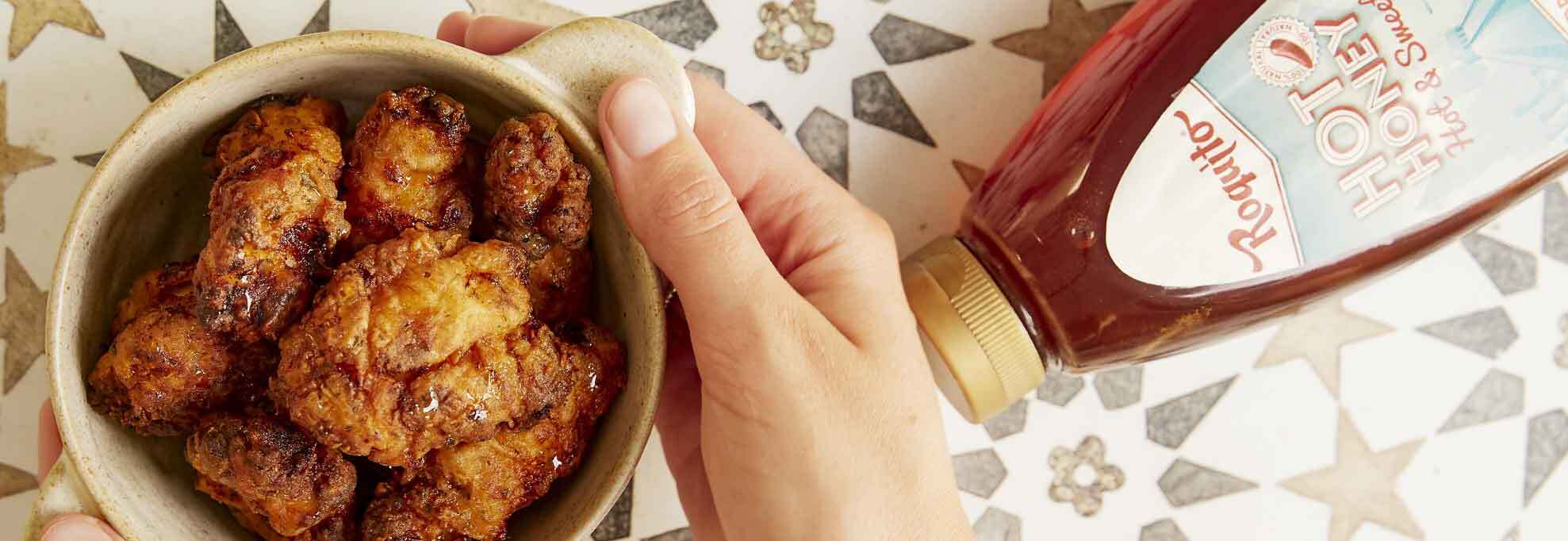 Bowl of crispy fried chicken pieces ready to be drizzled with Roquito Hot Honey for a sweet and spicy glaze.