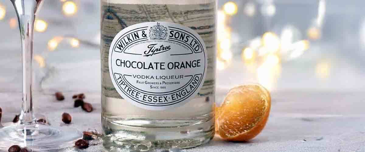 Tiptree-Wilkin-&-Sons-Chocolate-Orange-Vodka-Liqueur-next-to-a-martini-glass-on-a-snowy-winter-backdrop-with-fairy-lights