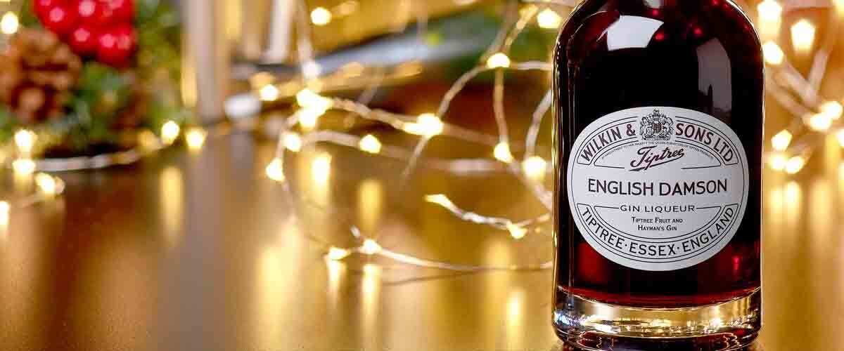 Tiptree-Wilkin-&-Sons-English-Damson-Gin-Liqueur-against-a-deep-red-christmas-background-with-fairy-lights